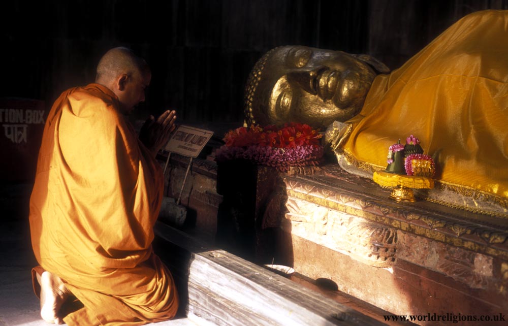 Statue of the `death of Buddha` with a monk praying - parinirvana - at Kusingara India
